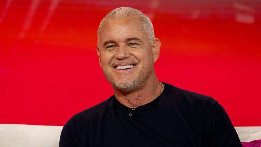 Eric Dane smiling while wearing a black shirt in a casual setting.