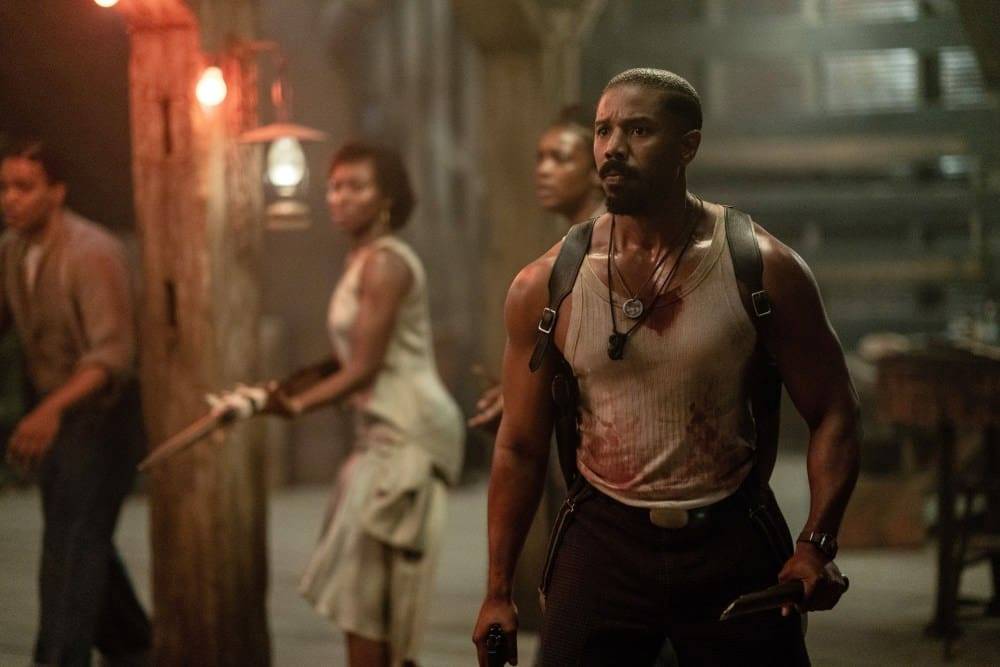A group of four characters in a dimly lit setting, with one man holding a weapon and showing signs of distress.