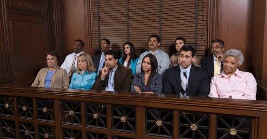 A group of diverse individuals seated in a jury box in a courtroom setting.