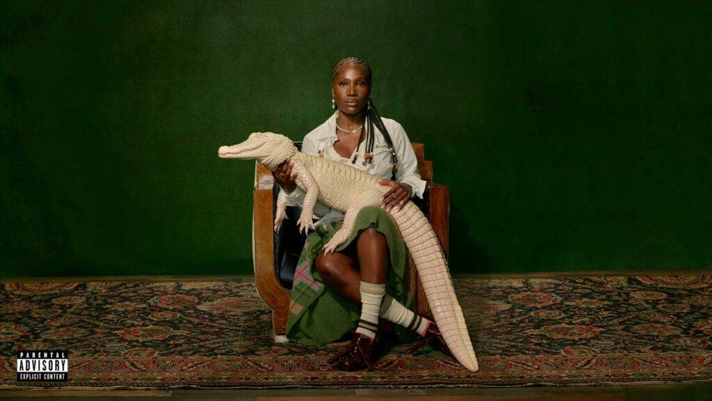 Individual seated on a chair holding a white alligator in a studio setting with a green background.