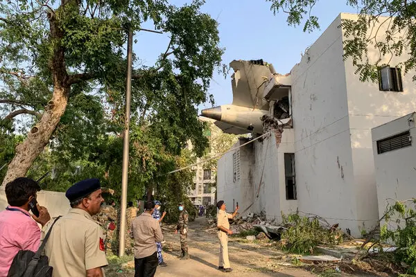 A building with an airplane wing protruding from its side, showing structural damage.