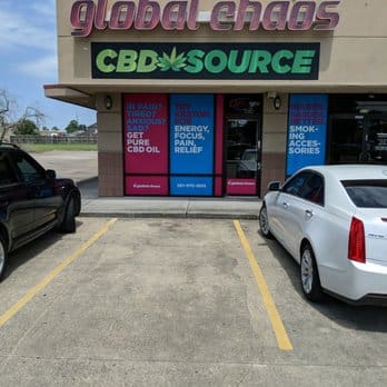 Storefront of CBD Source with Global Chaos signage and parking spaces in front.