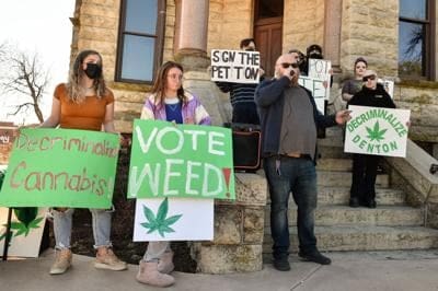 Group of protesters holding signs advocating for cannabis decriminalization in Denton, Texas.