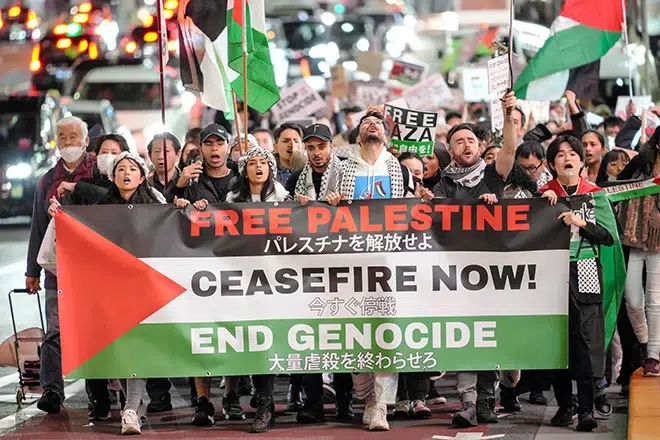 #freepalestine Group of protesters holding a large banner demanding freedom for Palestine and an end to genocide.