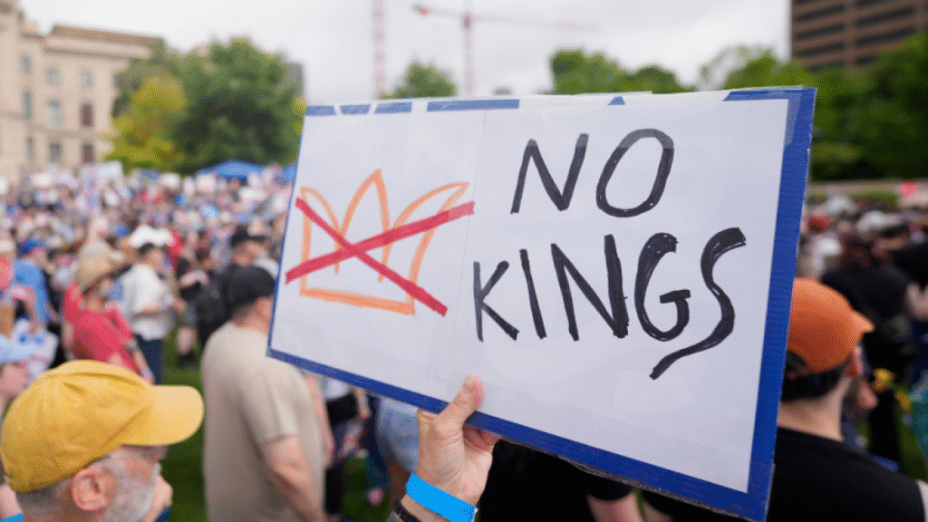 A protest sign held by an individual displaying the message 'No Kings' with a crossed-out crown symbol.