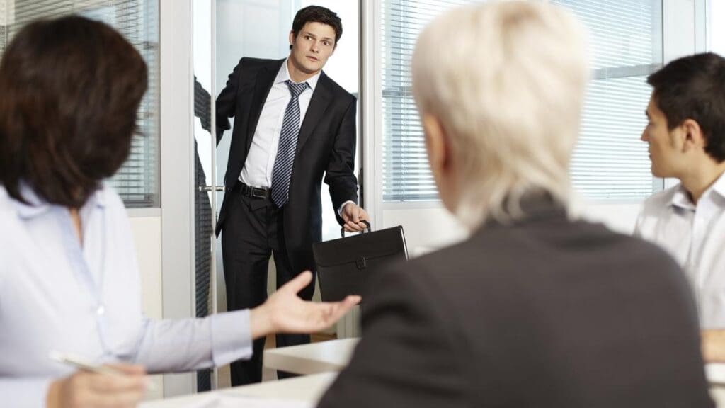 A businessman in a suit entering a meeting room while carrying a briefcase.