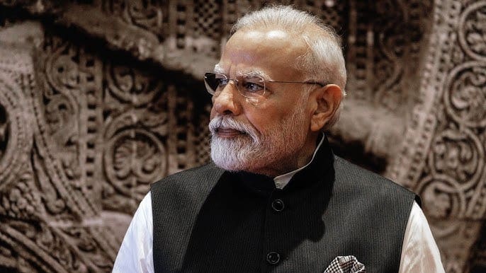 Man with silver hair and glasses wearing a black traditional vest and white shirt, looking to the side.