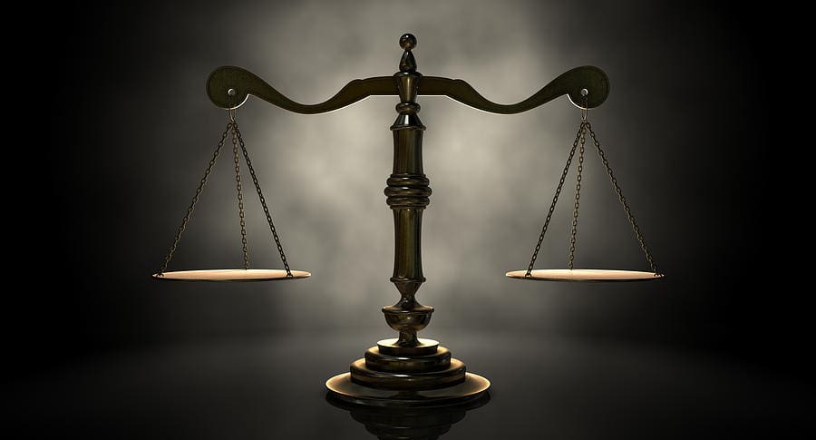 Bronze scales of justice with two empty pans suspended from a central beam.