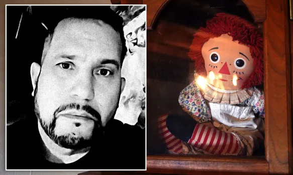 Raggedy Ann doll with red yarn hair and a patterned dress inside a wooden display case.