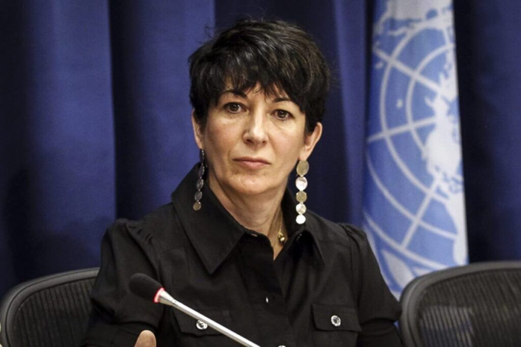 Susan Collins speaking at a press conference with a microphone and United Nations backdrop.