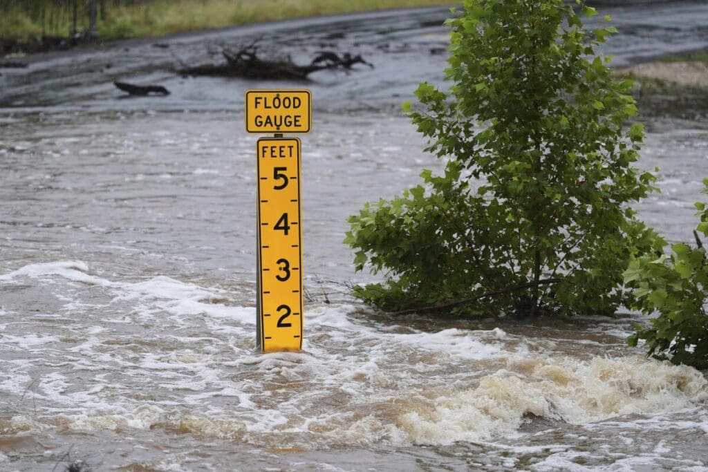 Yellow flood gauge displaying water levels marked in feet during a flood event.