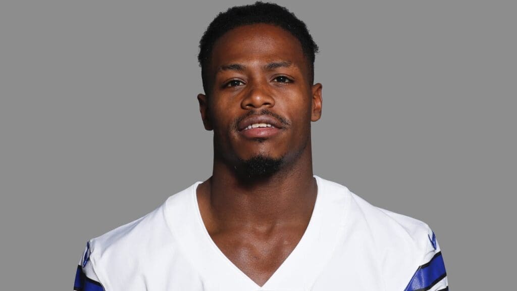Headshot of a football player wearing a white jersey with blue accents and a neutral expression.