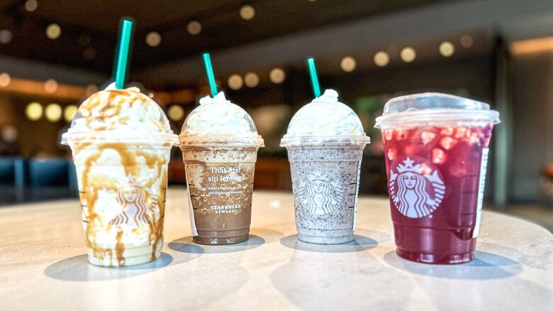 Four Starbucks drinks including frappuccinos and a refreshment with whipped cream and straws.