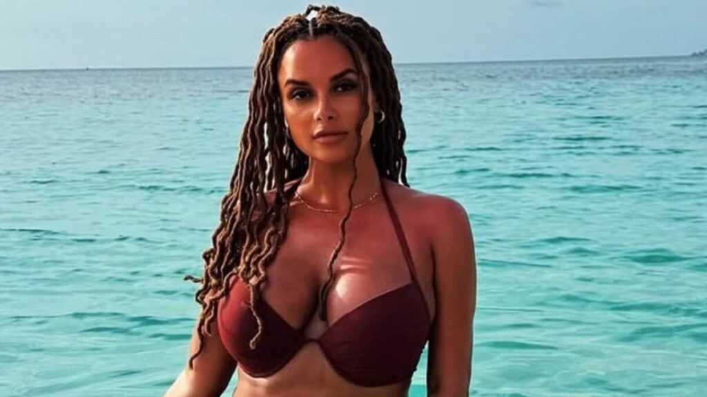 Woman with long braided hair wearing a brown bikini standing in the water.