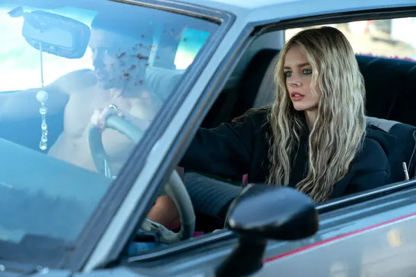 Young woman with long hair sitting in the driver's seat of a car, looking ahead.