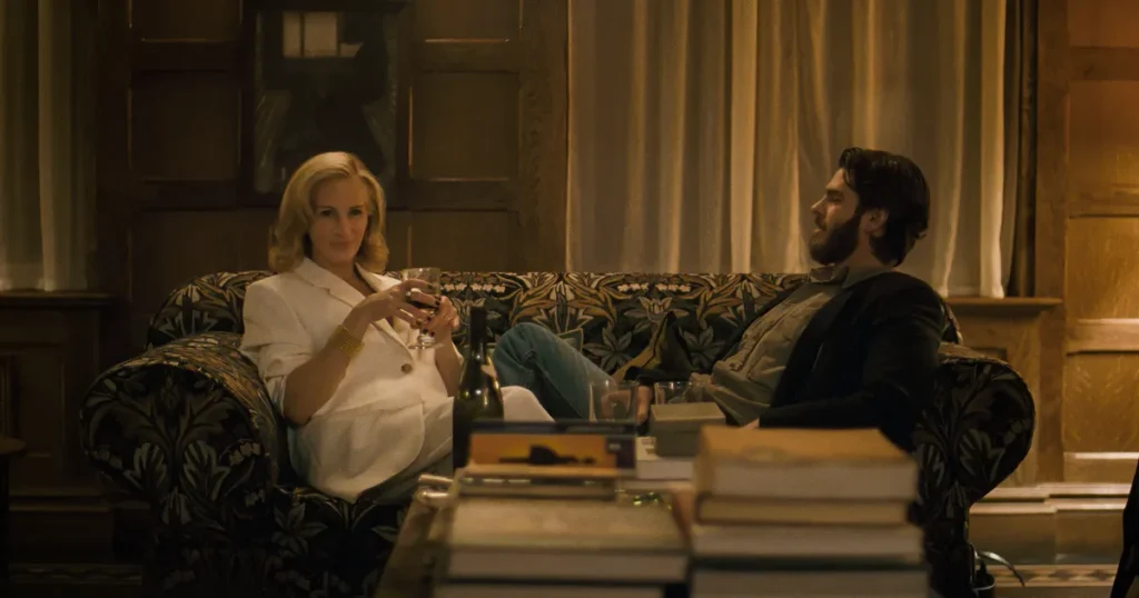 A scene with a woman holding a drink and a man seated on a couch, both engaged in conversation.