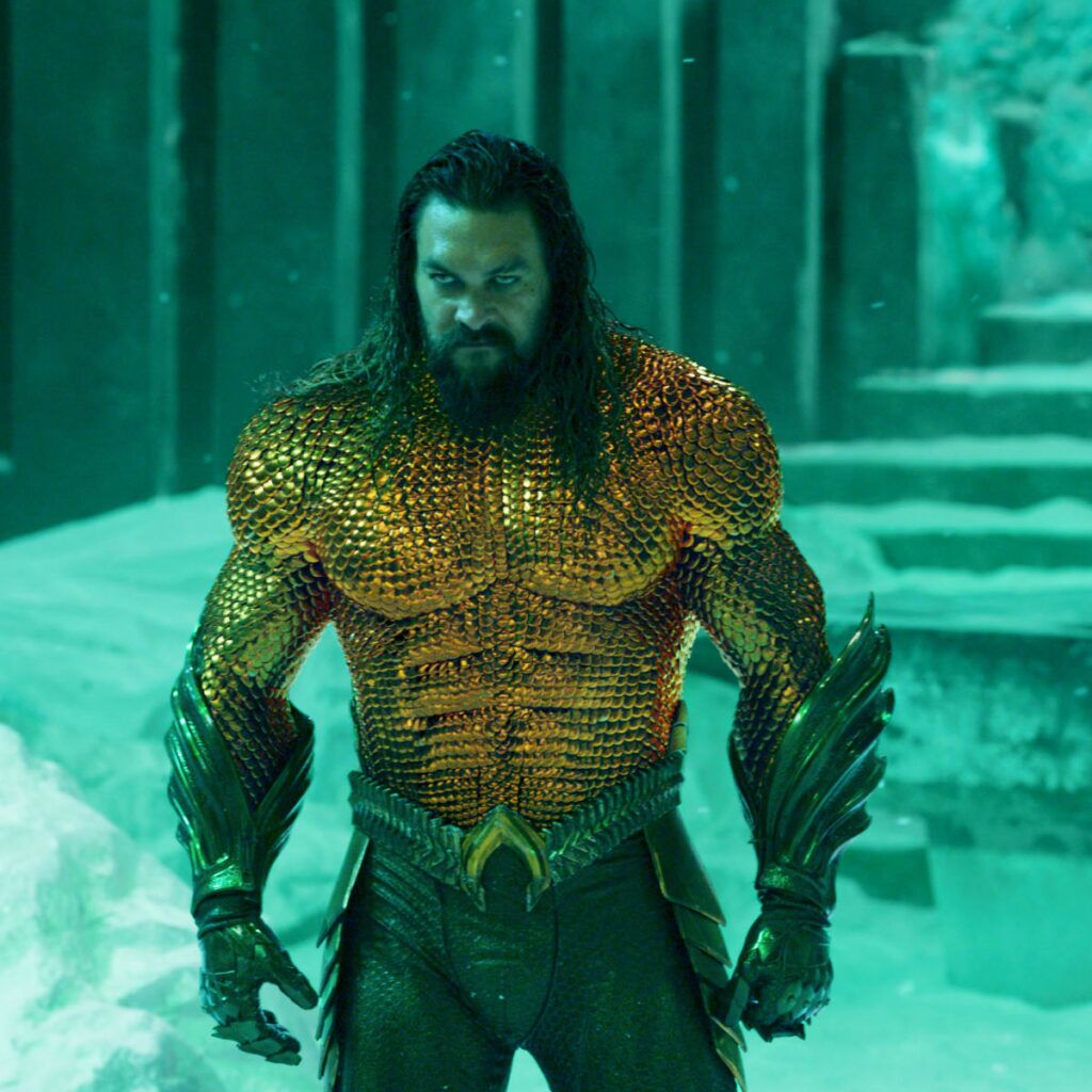 Aquaman character portrayed by Jason Momoa, wearing an orange and green costume with a serious expression.