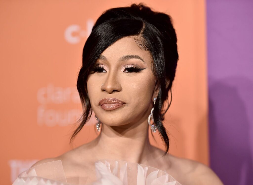Cardi B posing at an event with a neutral expression and elegant hairstyle.