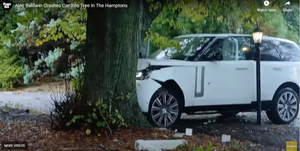 A white SUV that has crashed into a tree, showing damage to the front end.